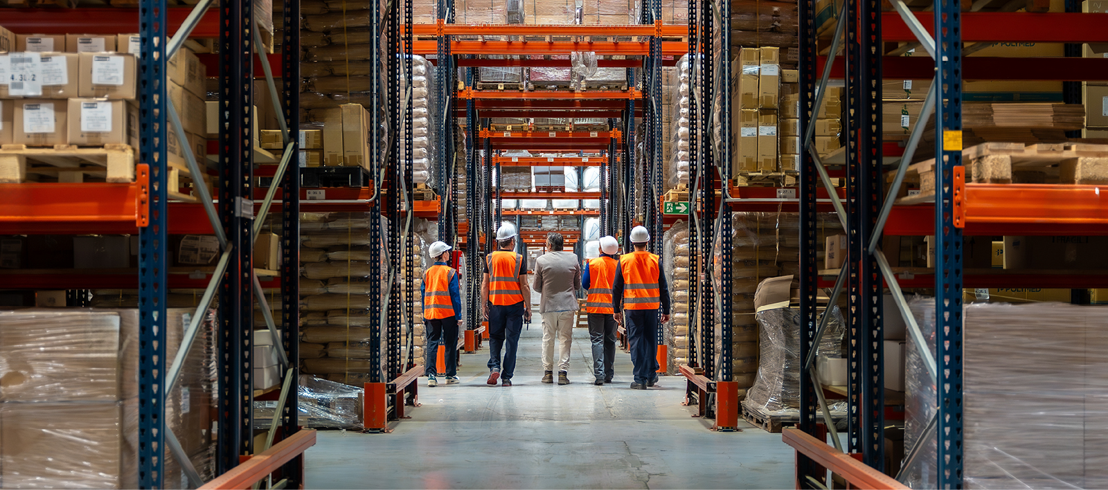 Warehouse team walking between stocked pallet racks